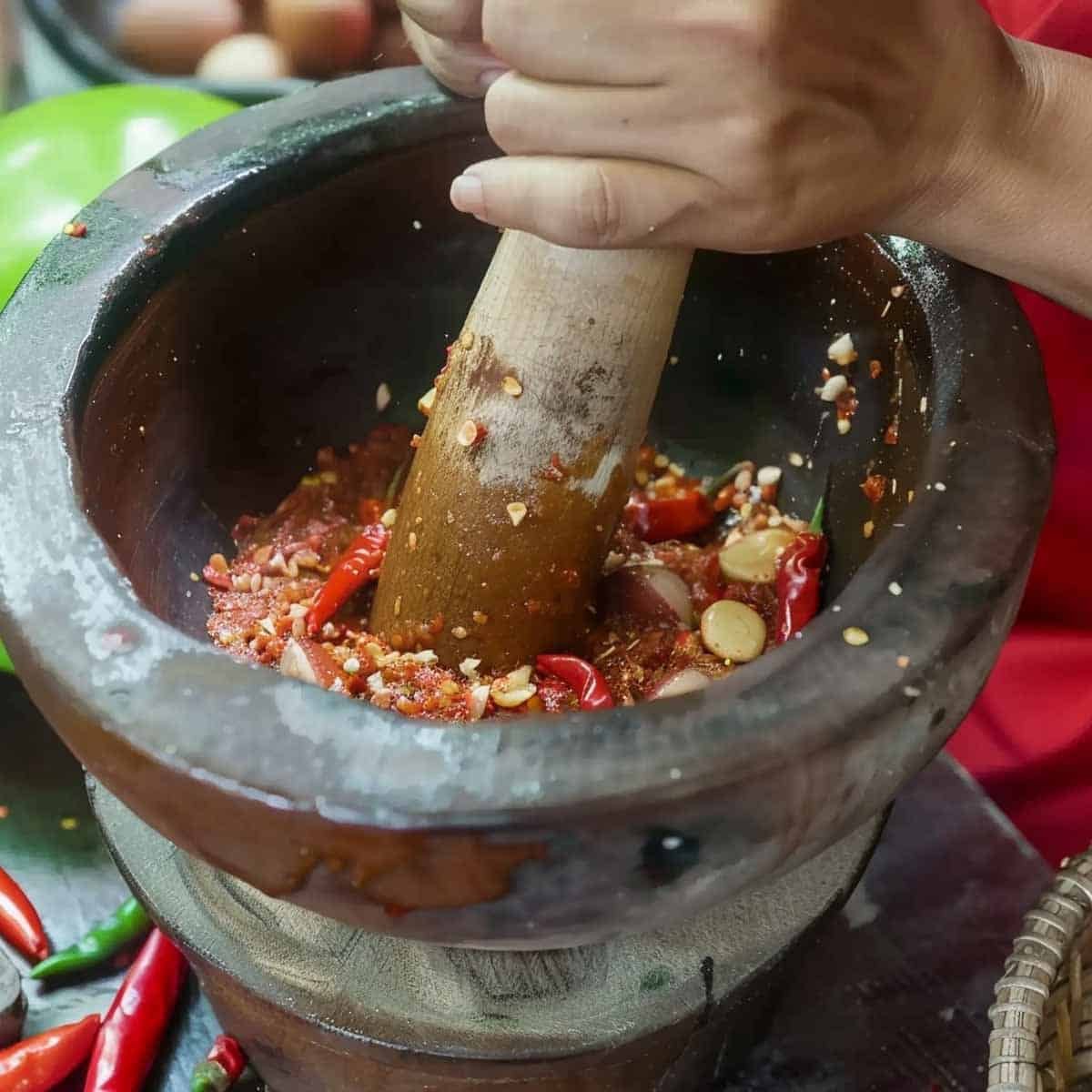 Mortar and pestalgrinding garlic and thai chili peppers