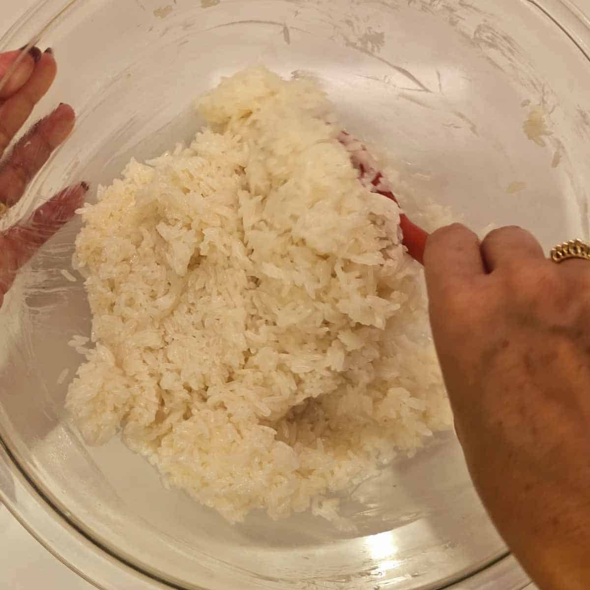 Mixing coconut sauce into sticky rice for Mango Sticky Rice preparation