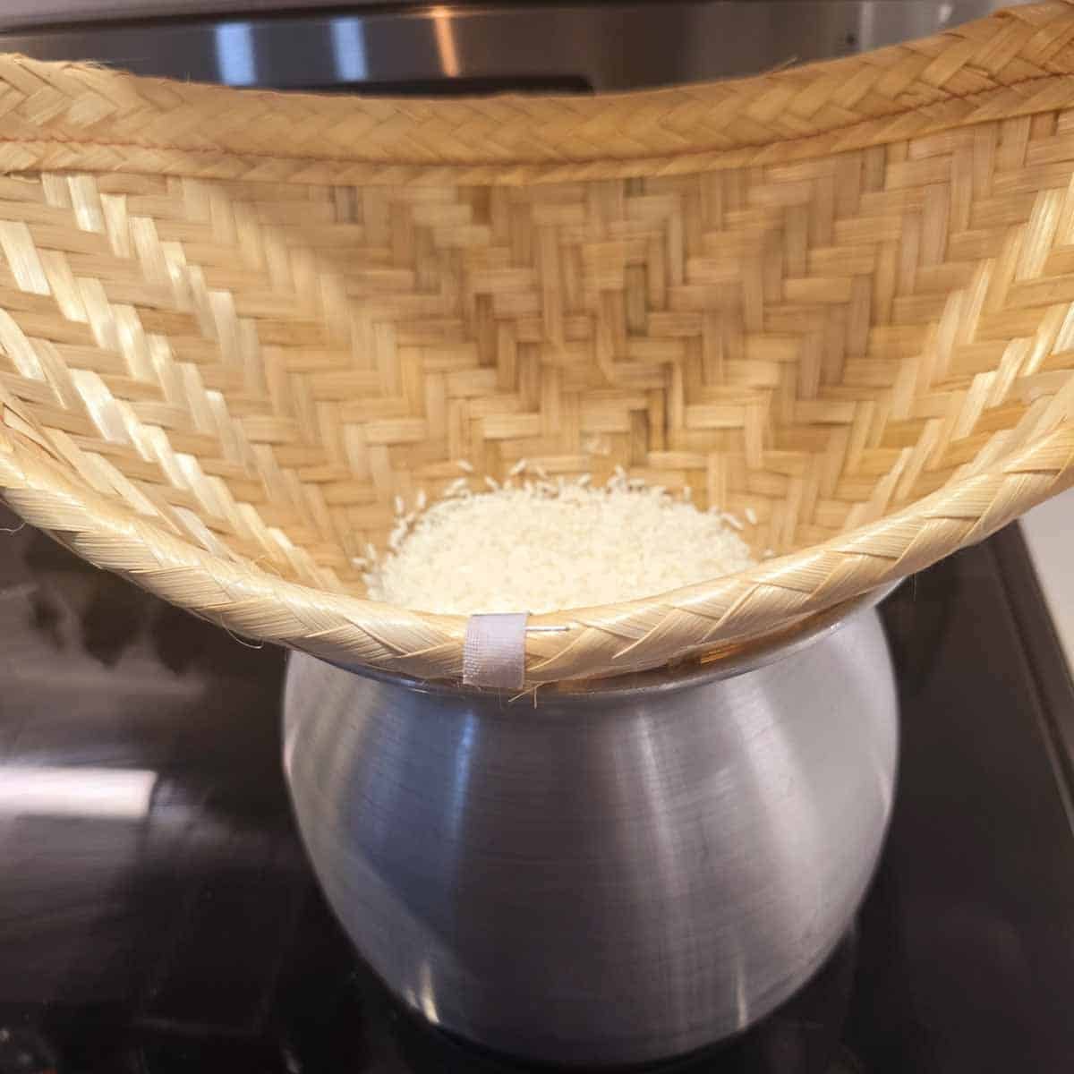 Sweet rice placed in a bamboo bowl over a steaming pot, ready for cooking.