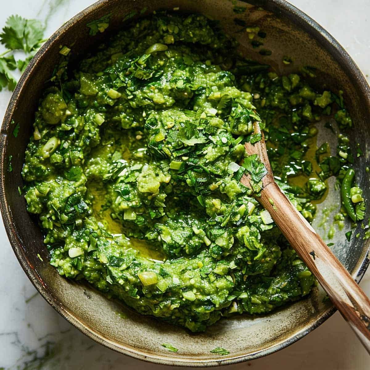 A wooden spoon mixes ingredients in a bowl for Thai chili dipping sauce