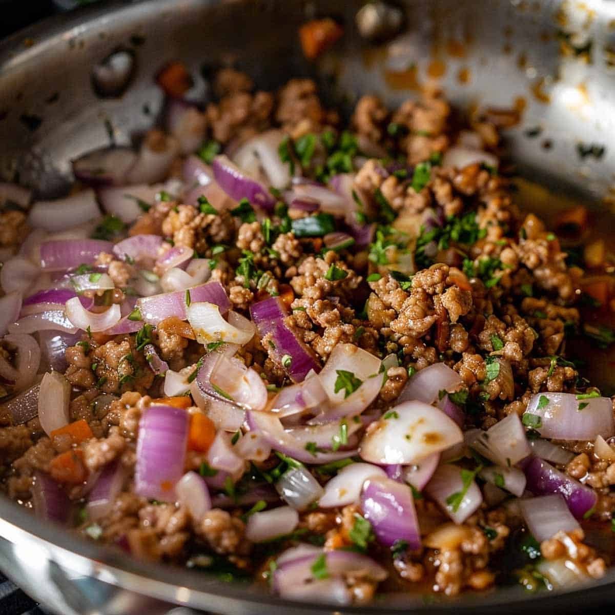Adding sliced onions to cooked pork for Thai Basil Pork (Pad Kra Pao Moo).