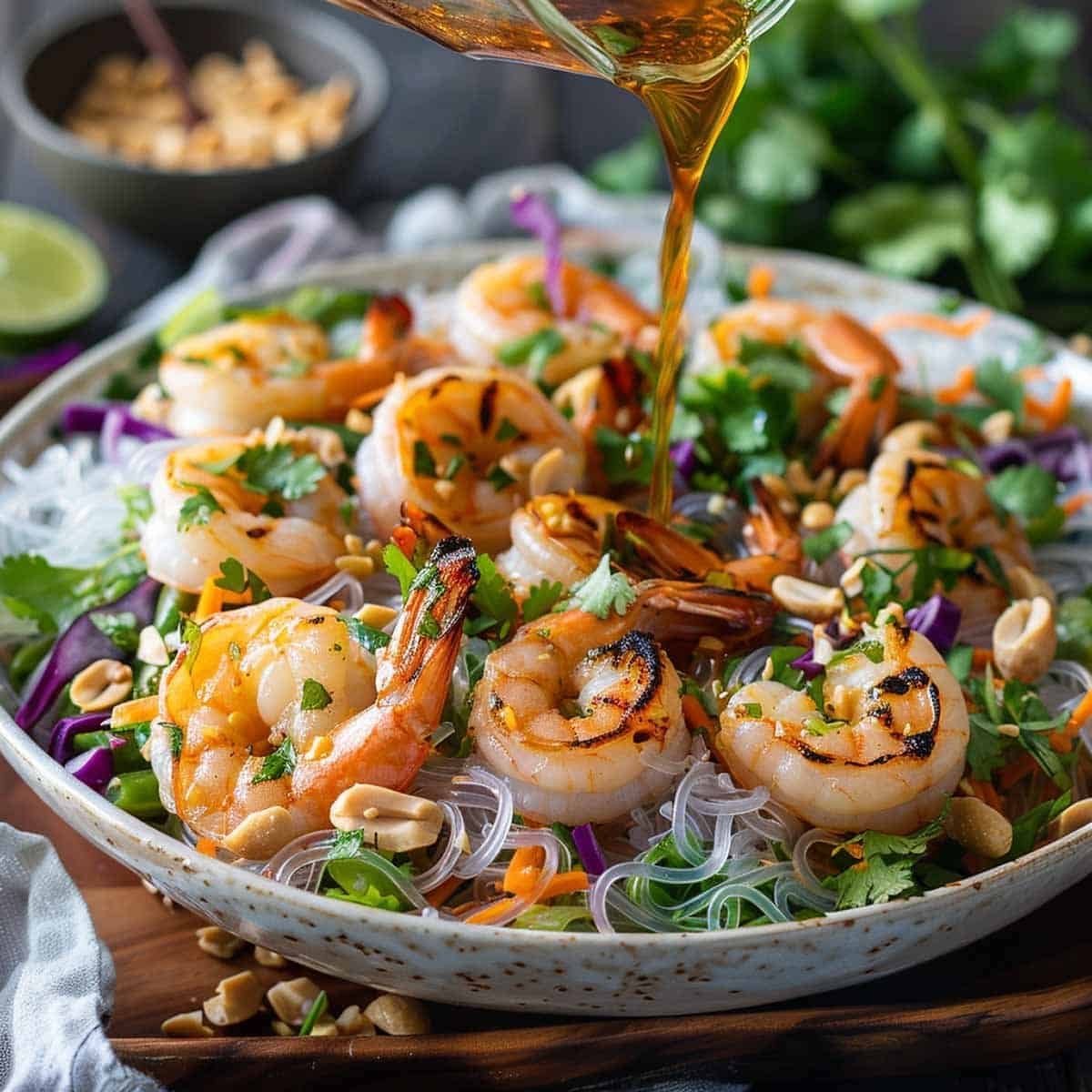 Dressing being poured over Yum Woon Sen glass noodle salad, ready to be tossed and served