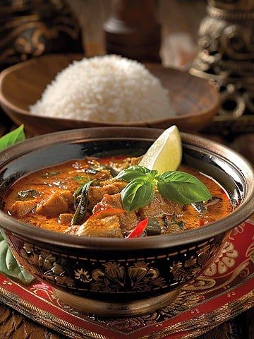 Panang Curry served in a bowl with steamed rice, garnished with fresh basil leaves.