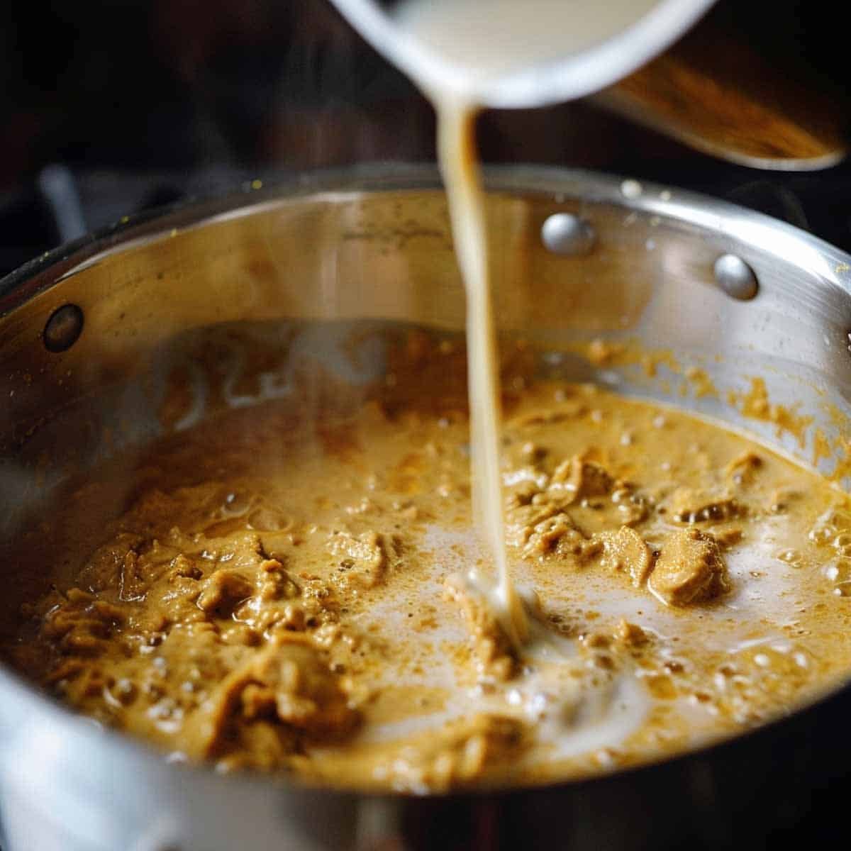 Pour coconut milk and water, stirring to combine with curry paste. Simmer gently to create a rich, creamy sauce that balances the heat.