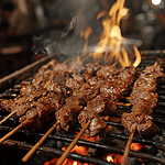 Moo Ping pork skewers cooking to perfection on an open flame grill