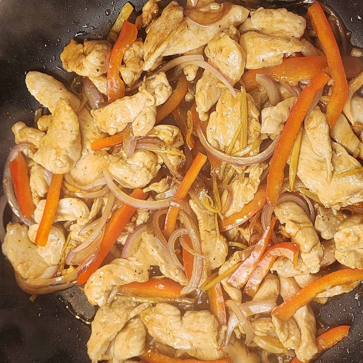 Chicken, peppers and onions cookig in a wol