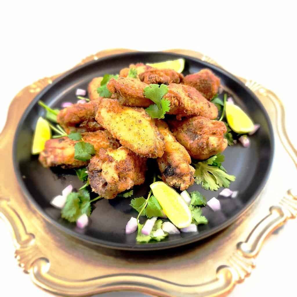 Crispy caramelized fish sauce chicken wings with golden-brown skin, garnished with chopped cilantro and sliced chilies for authentic Thai flavor