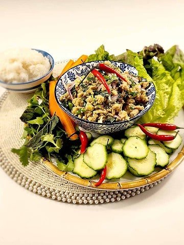 Thai Laab (Larb) salad served in a traditional ceramic bowl with fresh herbs, chili, lime and sticky rice