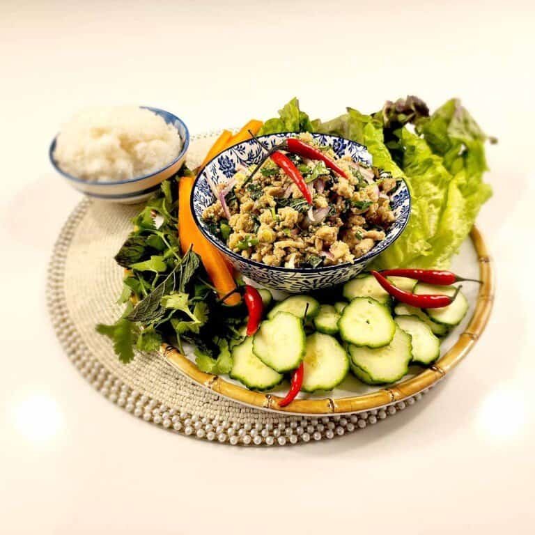 Thai Laab (Larb) salad served in a traditional ceramic bowl with fresh herbs, chili, lime and sticky rice