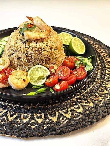 Traditional Thai Tom Yum Fried Rice with shrimp, beautifully plated with fresh cucumber slices and lime wedges ready to serve