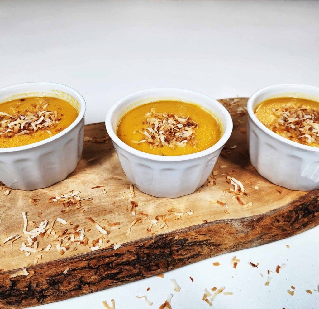 Sang Kaya Fak Thong in bowls topped with coconut flakes showing golden pumpkin custard texture.