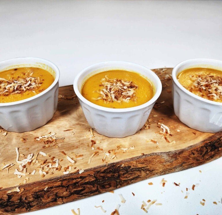 Sang Kaya Fak Thong in bowls topped with coconut flakes showing golden pumpkin custard texture.