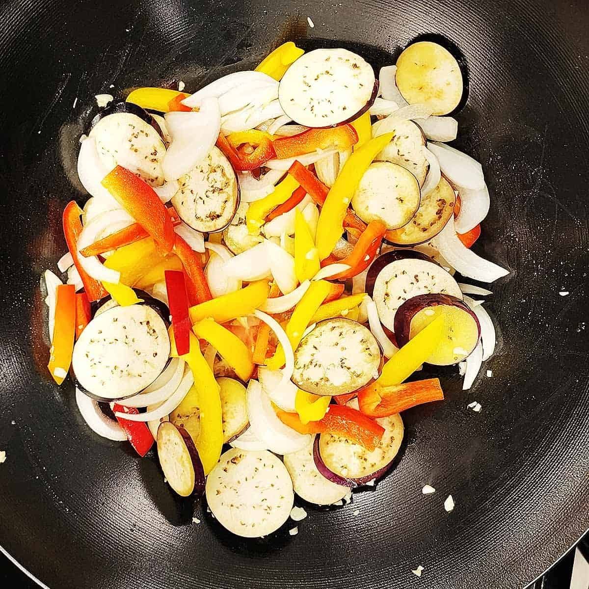 Colorful vegetables cooking in a wok with steam rising and visible sizzling