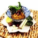 Aromatic golden curry paste in ceramic bowl garnished with red Thai chilies and surrounded by traditional ingredients