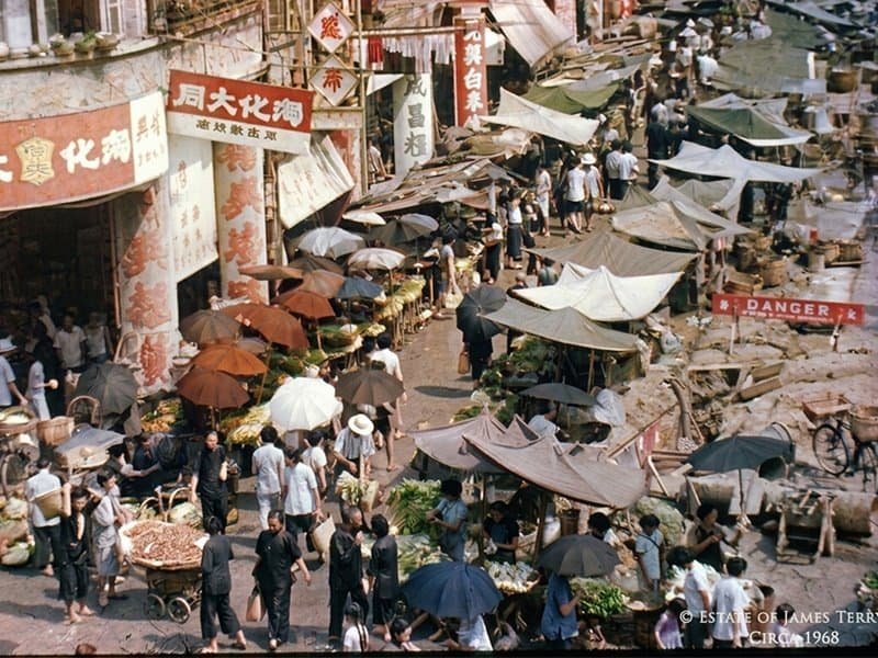 Vintage photo of busy Asian street market with vendors and umbrellas photographed from above circa 1968